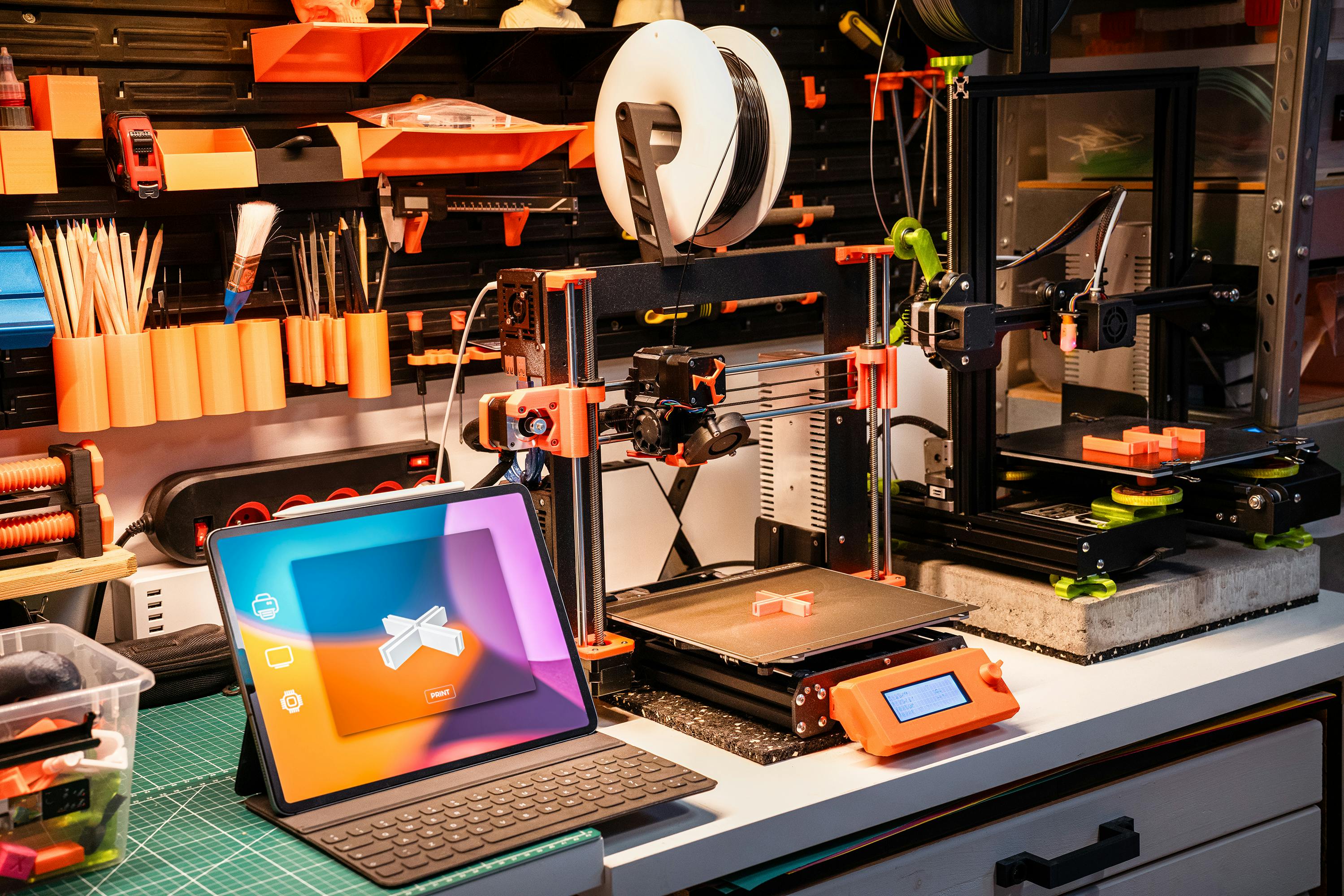 3d printers in a workbech with an ipad showing a CAD model