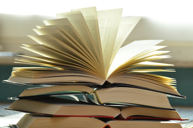 books stacked up with an open book at the top